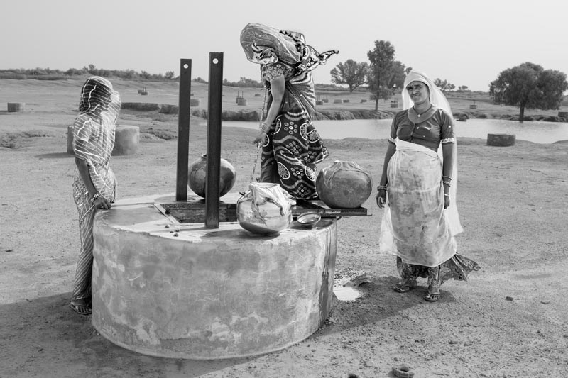 Water being drawn from a 'kuin'(shallow well) for filling drinking water containers - village Binjharwali, Bikaner district, Rajasthan